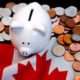 White piggybank on Canadian flag with coins around it