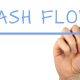 Hand writing CASH FLOW with blue marker