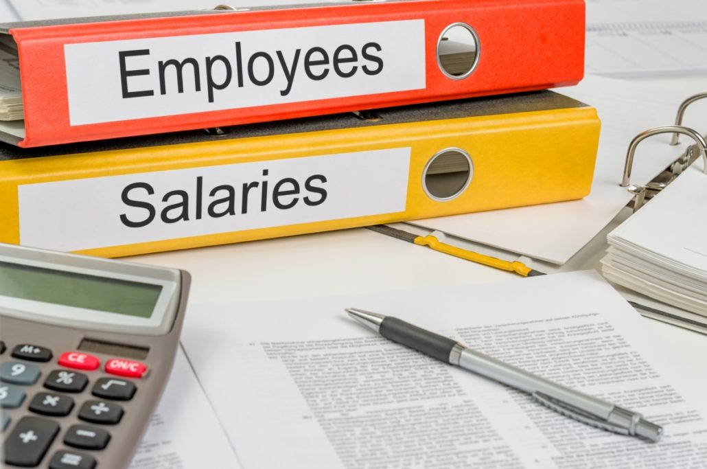 Employee binders with grey calculator, payroll paperwork