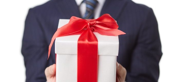 Man in blue suit holding white box with red ribbon